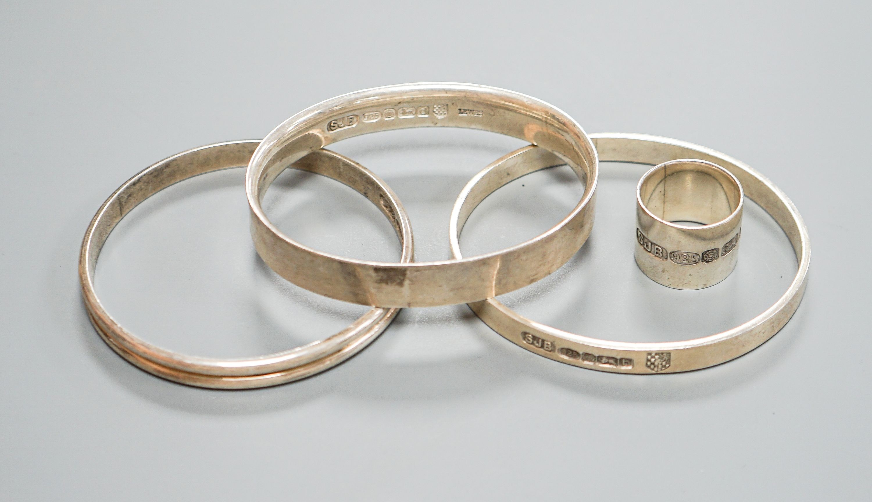 Three modern silver bangles and a large silver band, all by Simon J. Beer of Lewes